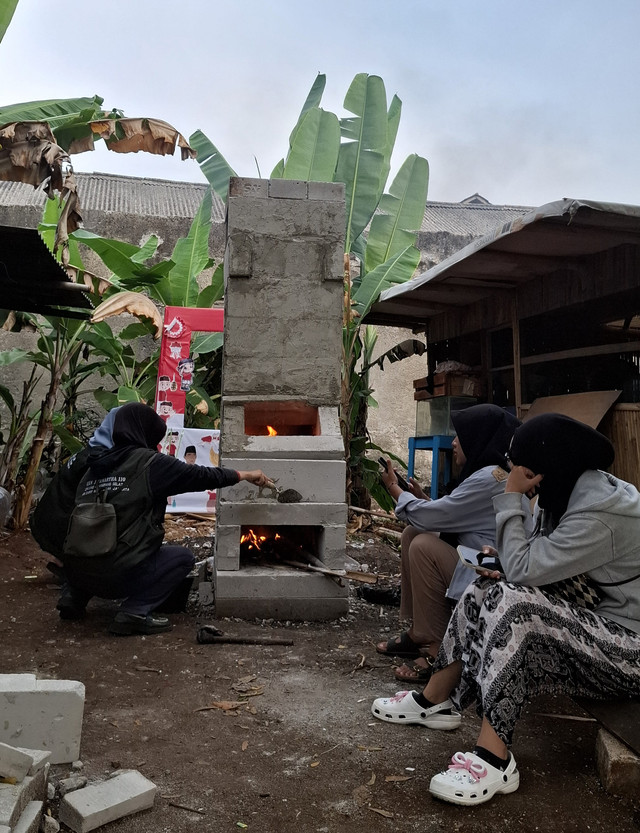 Mahasiswa KKN 110 Jivanartha bersama warga saat melakukan uji coba pengapian pada Rocket Stove yang baru selesai dibangun. Dok. Istimewa.
