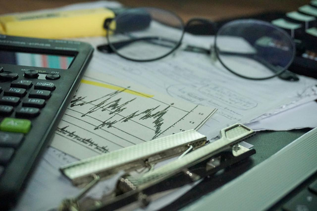 Image Credit to Berke Citak, https://unsplash.com/photos/a-desk-with-a-calculator-papers-eyeglasses-and-office-supplies-QV5VoI18Ld8
