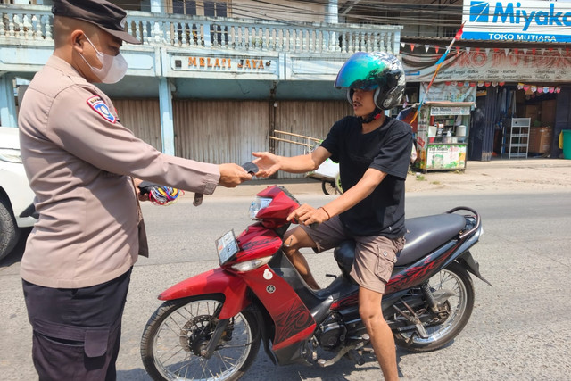 Anggota polisi dari Polres Bogor membagikan masker kepada warga dan pengendara, Minggu (6/9/2026). Foto: Dok. Istimewa
