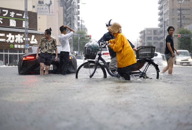 Warga berjalan di jalan yang tergenang akibat hujan deras di Nagoya, Jepang, Selasa (8/6/2026). Foto: Kyodo/via REUTERS