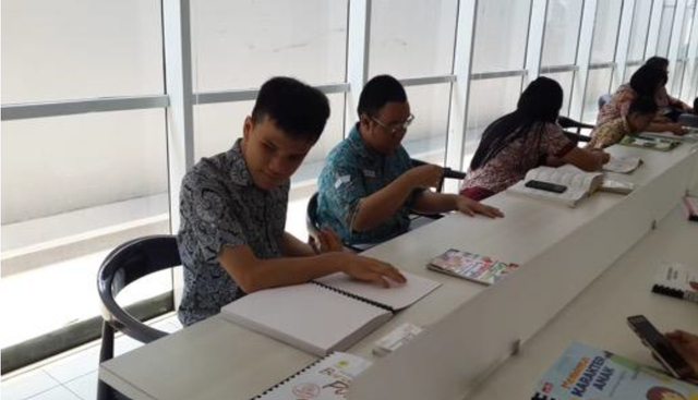 Pemustaka sedang membaca buku braille (sumber: Perpustakaan Nasional RI)