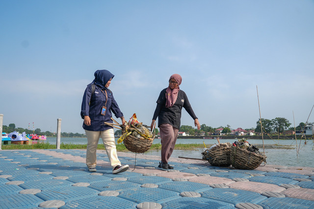 Account Officer PNM bersama Leni saat membersihkan sampah di tepi Danau Sipin, Jambi. Foto: Dok. PNM