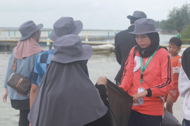 Melakukan penyisiran sampah di tepi laut Kepulauan Seribu