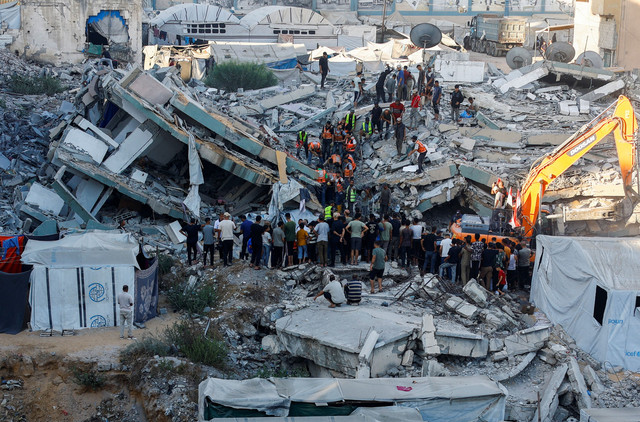 Orang-orang berkumpul saat petugas Pertahanan Sipil berupaya menyelamatkan orang-orang yang terjebak di bawah reruntuhan bangunan tempat tinggal yang rusak akibat serangan Israel sebelumnya di Kota Gaza, Rabu (16/9/2026). Foto: Mahmoud Issa/REUTERS