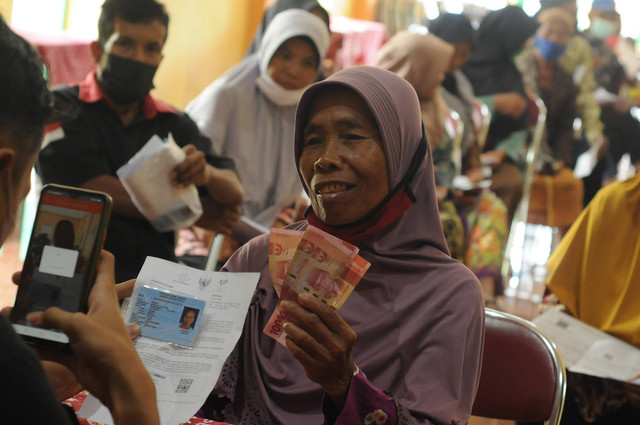 Petugas Kantor Pos Indonesia memfoto warga penerima manfaat saat penyaluran bantuan langsung tunai bahan bakar minyak (BLT BBM) di Mudal, Boyolali, Jawa Tengah, Kamis (8/9/2022). Foto: Aloysius Jarot Nugroho/Antara Foto