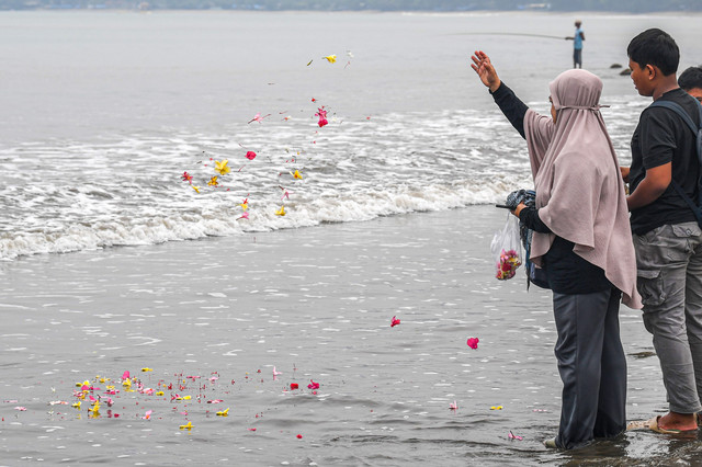 Istri Arie Basuki Yanti (kanan) menabur bunga didampingi Bintang di pantai Pagedongan, Pandeglang, Banten, Jumat (18/9/2026). Foto: Paramayuda/ANTARA FOTO