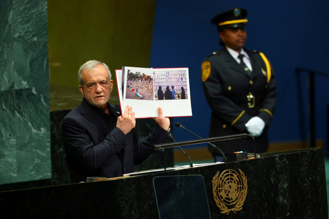 Presiden Iran Masoud Pezeshkian memegang sebuah foto saat berpidato dalam Sidang Majelis Umum PBB ke-81 di Markas Besar PBB di New York, AS, Rabu (23/9/2026). Foto: Mike Segar/REUTERS