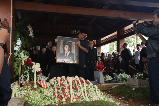 Wakil Gubernur DKI Jakarta Rano Karno memegang foto almarhum Guruh Soekarnoputra di TPU Karet Bivak, Jakarta, Sabtu (26/9/2026). Foto: Syawal Febrian Darisman/kumparan