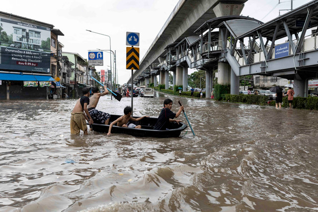 Warga menerjang banjir di distrik Bang Bua, Bangkok, Thailand, Sabtu (26/9/2026). Foto: Wikus de Wet / AFP