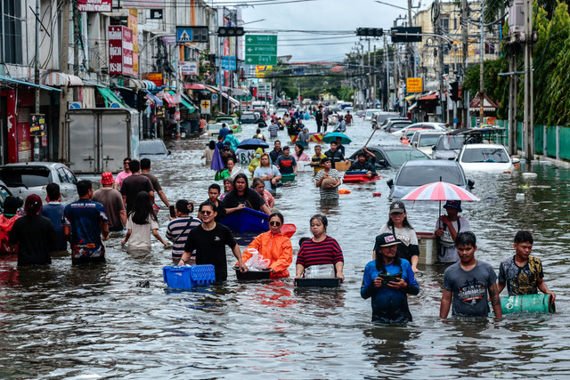 Warga berjalan menerjang banjir saat hujan deras di Bangkok, Thailand, Minggu (27/9/2026). Foto: Patipat Janthong/ REUTERS