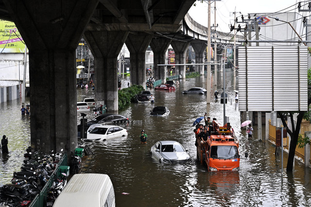 Sebuah truk melintas di dekat kendaraan-kendaraan yang ditinggalkan dan terjebak dalam genangan banjir di kawasan Ramkhamhaeng, Bangkok, Thailand, Minggu (27/9/2026). Foto: Lillian Suwanrumpha / AFP