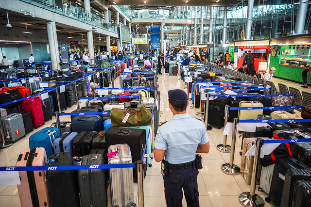 Seorang anggota keamanan bandara berdiri di samping bagasi dari penerbangan Thai Airways di Bandara Internasional Suvarnabhumi, setelah hujan lebat dan banjir mengganggu operasional darat maskapai tersebut, di Bangkok, Thailand, Selasa (29/9/2026). Foto: Athit Perawongmetha/REUTERS