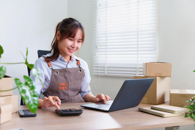 Seorang pelaku UMKM sedang mengelola keuangan dan aktivitas bisnis menggunakan laptop serta kalkulator untuk mendukung pencatatan dan pengembangan usahanya.Foto : ShutterStock.