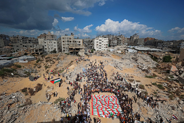 Para pelayat berkumpul untuk prosesi pemakaman massal sebanyak 105 jenazah yang tewas akibat terkena reruntuhan blok perumahan al-Taj yang hancur akibat serangan Israel di al-Yarmouk, Gaza, pada 1 Oktober 2026. Foto: Omar AL-QATTAA / AFP