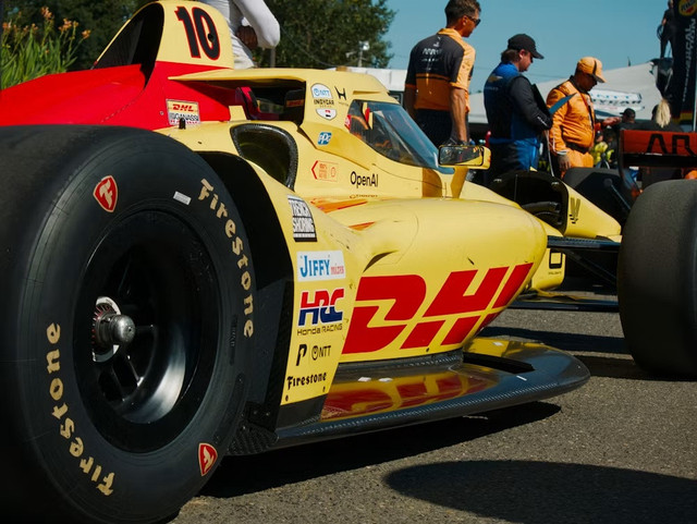 Logo DHL pada mobil balap menjadi gambaran keterlibatan perusahaan multinasional di balik operasi global Formula 1. Foto: Unplash. 