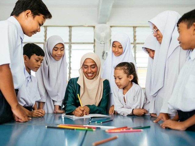 Seorang guru berhijab mendampingi siswa dalam kegiatan pembelajaran di kelas. Foto: Irwan Zahuri/Pexels.