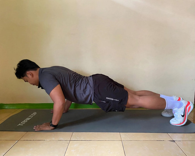 Foto tersebut memperlihatkan seorang pria yang sedang melakukan latihan push-up di atas matras di dalam rumah. Latihan ini merupakan salah satu contoh bodyweight training atau latihan beban tubuh yang efektif untuk melatih kekuatan otot dada, lengan, dan otot inti tanpa memerlukan alat gym. Dokumentasi pribadi kegiatan (04/10/2026)