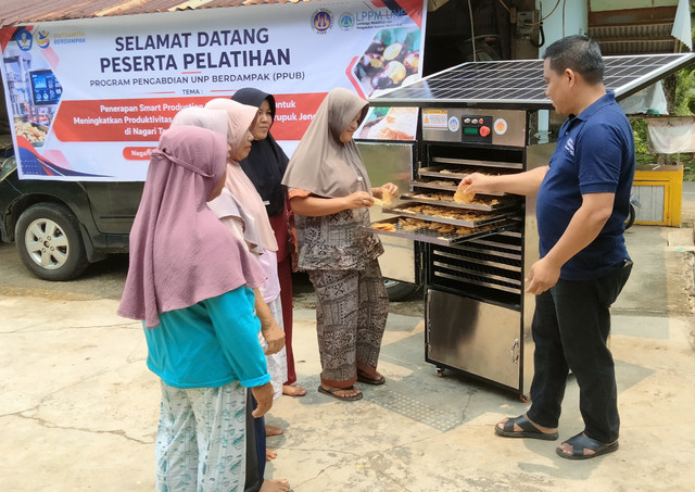 Ibu Lili Suryani memeriksa Smart Solar Dryer IoT di Nagari Tanjung, Sijunjung (Dokumentasi PkM)