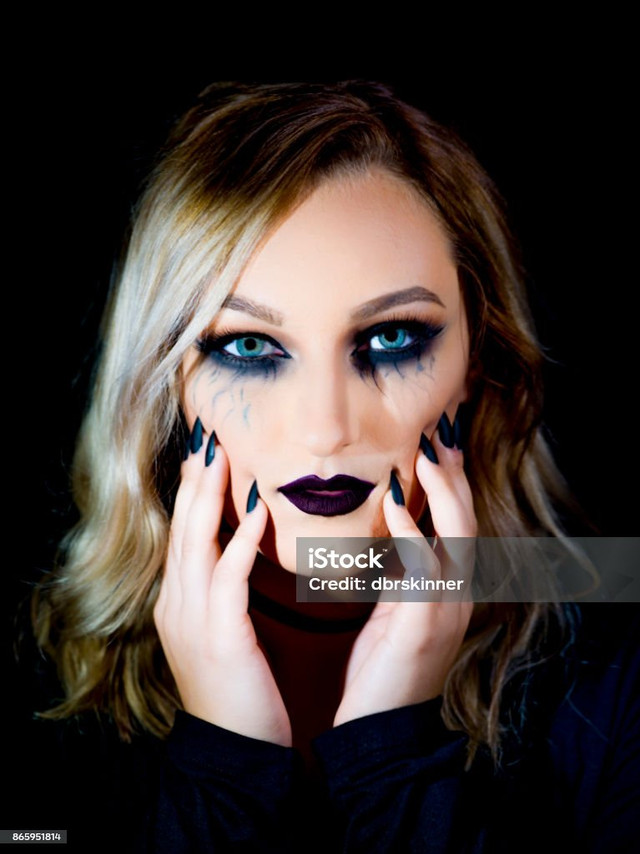 Seorang Perempuan bermakeup gotik dengan riasan mata gelap, bibir ungu kehitaman, dan kuku hitam yang memberikan kesan dramatis dan misterius. (Sumber : iStock)