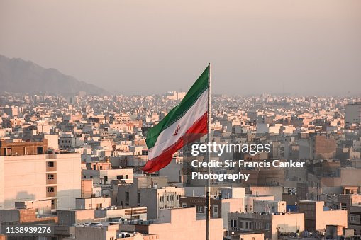 Iranian flag waving with city skyline on background in Tehran, Iran
