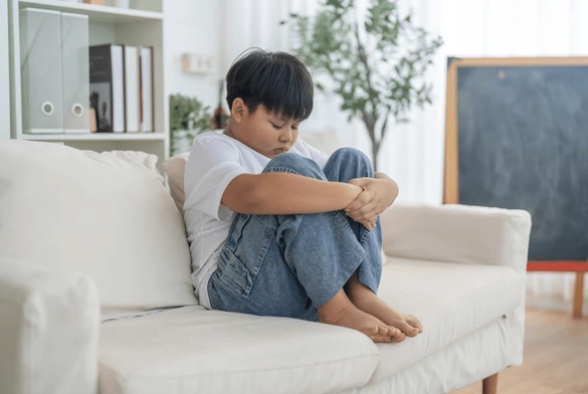 Anak laki-laki duduk sendirian menekuk lutut ketika menjadi korban kekerasan. Foto: Shutterstock.