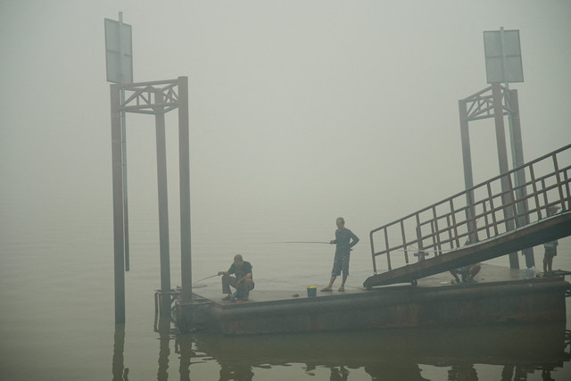 Warga memancing di Sungai Musi saat kabut asap akibat kebakaran hutan menyelimuti daerah tersebut di Palembang, Sumatera Selatan, Kamis (15/10/2026). Foto: Abriansyah Liberto/REUTERS