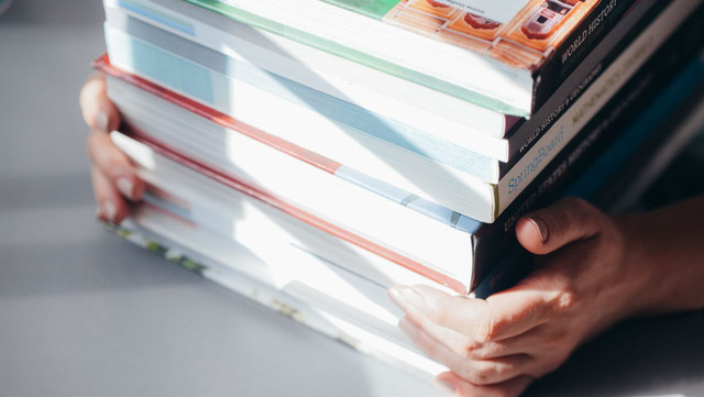 Photo by Kindel Media: https://www.pexels.com/photo/a-person-holding-a-stack-of-books-7054519/