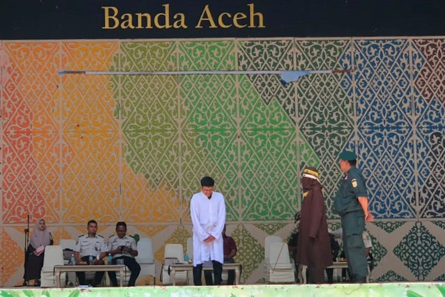 Seorang anggota polisi Syariah mencambuk seorang pria yang dinyatakan bersalah di bawah hukum syariah Islam yang ketat di Banda Aceh, Kamis (15/10/2026). Foto: kumparan