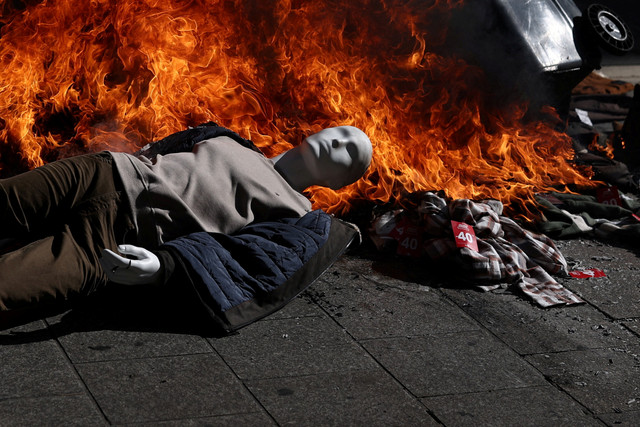 Sebuah manekin dari toko yang dijarah terlihat di tengah benda-benda yang terbakar saat demonstrasi menentang tingginya biaya hidup di Marseille, Prancis, Sabtu (17/10/2026). Foto: Manon Cruz/REUTERS