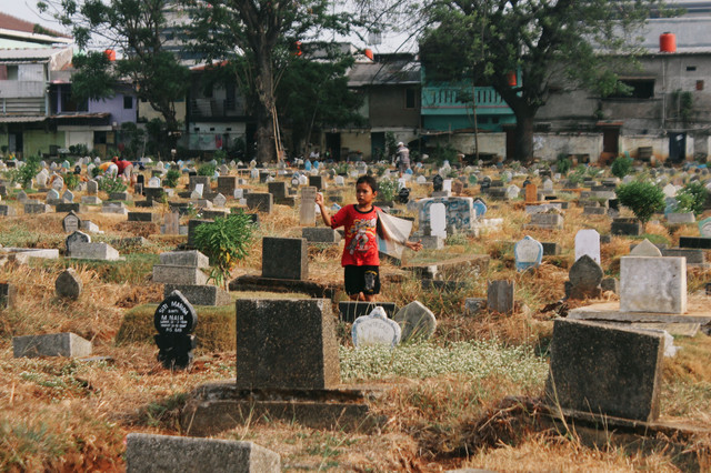 Seorang Anak Bermain Di Hamparan Makam TPU Prumpung//Foto: Raja Ravanda