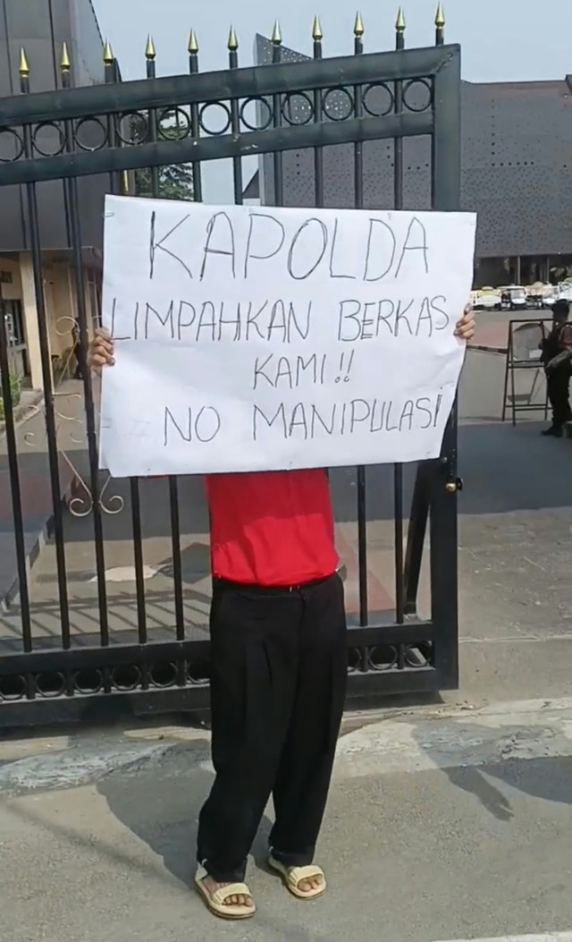 Seorang ibu bernama Anita Bertawaty melakukan aksi protes seorang diri di depan Mapolda Banten, Senin (19/10). Aksi ini ia lakukan karena kasus dugaan pengeroyokan yang dialami anaknya yang berinisial SD (29) mandek. Foto: Dok. Istimewa