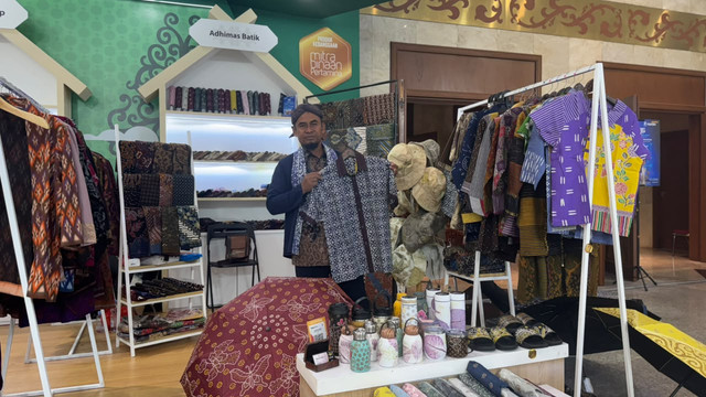 Suyanto memperkenalkan beragam produk Adhimas Batik, UMKM binaan Pertamina asal Klaten, dalam pameran INACRAFT 2026. Foto: kumparan/Maharani Sagita.