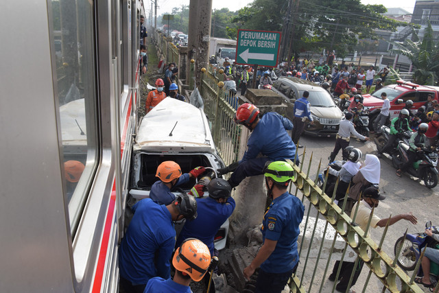 Sejumlah petugas berusaha mengevakuasi mobil Honda Mobilio yang tertabrak KRL Commuterline KA 1077 (Bogor-Jakarta Kota) di kawasan Rawageni, Ratu Jaya, Cipayung, Depok, Jabar, Rabu (20/4/2022). Foto: Andika Wahyu/ANTARA FOTO