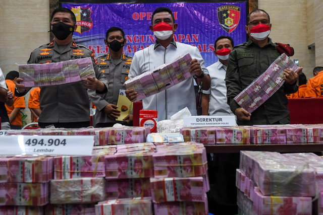 Dirtipideksus Bareskrim Polri Brigjen Pol Whisnu Hermawan (tengah) menunjukkan barang bukti mata uang dolar dan rupiah palsu saat rilis pengungkapan kejahatan mata uang palsu di Bareskrim Mabes Polri, Jakarta, Selasa (1/3/2022).  Foto: Galih Pradipta/ANTARA FOTO