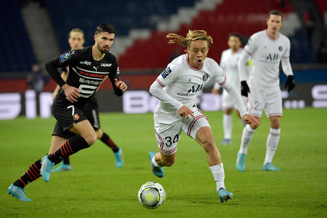 Pemain Paris Saint-Germain (PSG) Xavi Simons berebut bola dengan pemain Rennes pada pertandingan lanjutan Liga Prancis di Stadion The Parc des Princes, Paris, Prancis, Jumat (11/2/2022).  Foto: JULIEN DE ROSA / AFP
