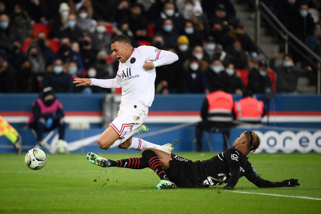 Pemain Paris Saint-Germain (PSG) Kylian Mbappe berusaha melewati pemain Rennes pada pertandingan lanjutan Liga Prancis di Stadion The Parc des Princes, Paris, Prancis, Jumat (11/2/2022).  Foto: JULIEN DE ROSA / AFP
