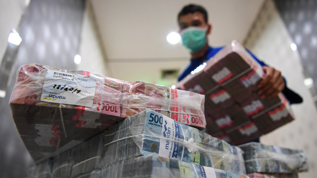 Pegawai menghitung uang tunai pecahan Rp100 ribu dan Rp50 ribu yang akan dikirimkan ke kantor cabang di Sentra Kas Bank Mandiri, Jakarta, Rabu (6/4/2022). Foto: M Risyal Hidayat/ANTARA FOTO