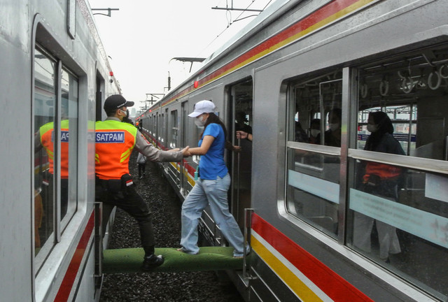 Petugas membantu penumpang KRL Commuterline berpindah rangkaian kereta di kawasan Cipinang, Jakarta Timur, Rabu (23/3/2022).  Foto: Paramayuda/ANTARA FOTO