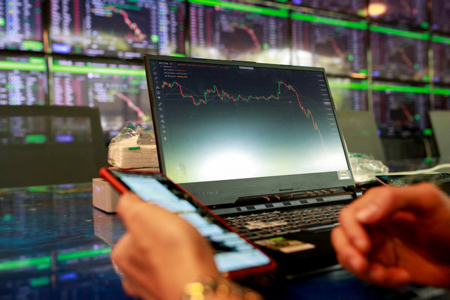 Pengunjung melihat grafik harga terbaru berbagai cryptocurrency. Foto: Soe Zeya Tun/REUTERS