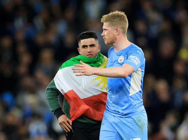 Pemain Manchester City Kevin De Bruyne bersama penonton yang masuk lapangan mengenakan bendera Italia pada pertandingan Liga Champions Leg Pertama Semi Final di Stadion Etihad, Manchester, Inggris. Foto: Lee Smith/Reuters