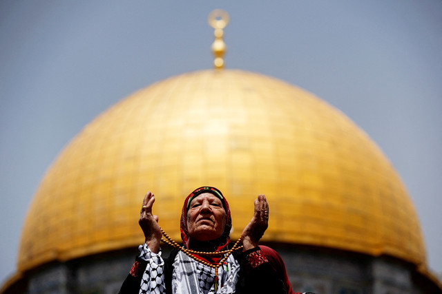 Wanita Muslim berdoa pada Jumat terakhir Ramadhan di depan Dome of the Rock (Kubah Batu), di kompleks Masjid Al-Aqsa di Kota Tua Yerusalem, Jumat (29/4/2022). Foto: Ammar Awad/REUTERS