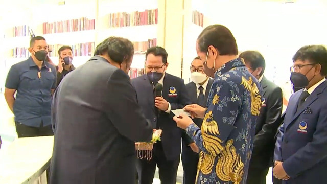 Ketum NasDem Surya Paloh memberikan Kartu Perpustakaan Panglima Item NasDem atas nama Jan Ethes dan Sedah Mirah ke Presiden Jokowi, Selasa (22/2/2022). Foto: Youtube/NasDem TV