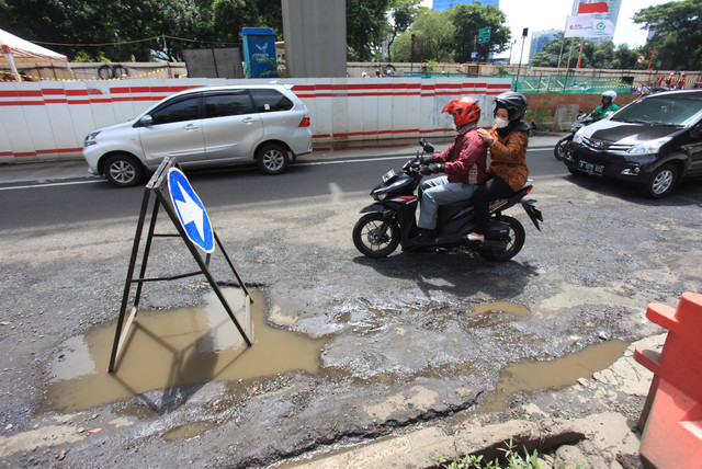 Pengendara motor melewati jalan yang rusak di Jalan Rasuna Said, Kuningan, Jakarta, Selasa (22/2/2022). Foto: Reno Esnir/ANTARA FOTO
