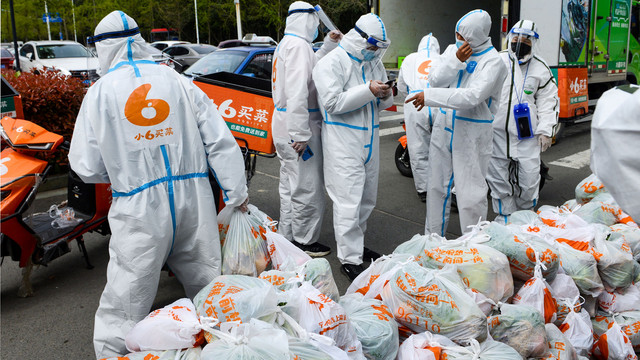 Petugas pengiriman mengenakan alat pelindung diri (APD) saat mengirimkan makanan yang dibeli secara online di Ningbo di provinsi Zhejiang timur China, Sabtu (2/4/2022). Foto: STR/AFP