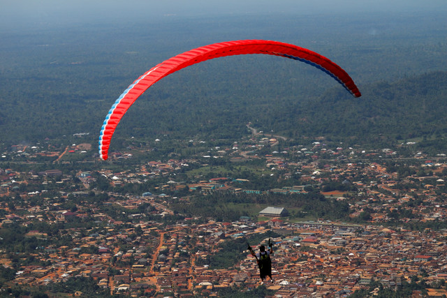 Seorang paraglider terbang dengan seorang penumpang selama festival paralayang Paskah tahunan di Kwahu-Atibie, Ghana. Foto: Francis Kokoroko/REUTERS