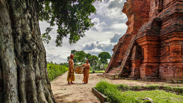 Dua warga bertemu di sekitar Candi Wringin Lawang dibangun pada masa Kerajaan Majapahit di Jawa Timur, Indonesia. Foto: livyah08/Shutterstock.