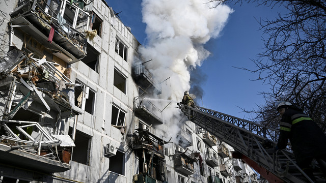 Petugas pemadam kebakaran bekerja pada kebakaran di sebuah gedung setelah pemboman di kota Chuguiv, Ukraina timur, Ukraina, Kamis (24/2/2022). Foto: Aris Messinis/AFP