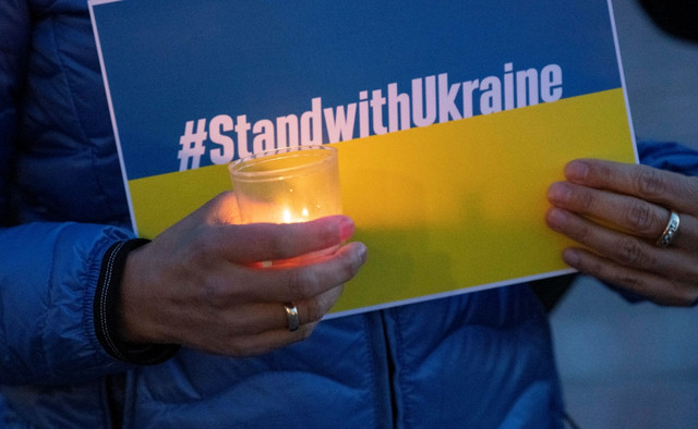 Sejumlah warga Jerman menyalakan lilin dan disusun menjadi tulisan Ukraina di depan Kastil Baru di Stuttgart, Jerman selatan, Sabtu (12/3/2022). Foto: Thomas Kiensle/AFP