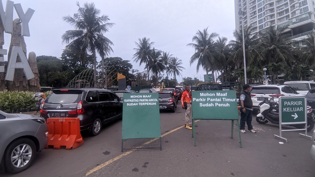 Petugas berdiri di papan peringatan saat kendaraan memadati Taman Impian Jaya Ancol, Jakarta Utara, Selasa (3/5/2022).
 Foto: Jonathan Devin/kumparan