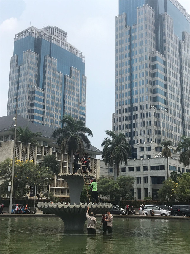 Seorang remaja naik di atas air mancur di kawasan Patung Kuda. Aksinya itu mengundang perhatian massa. Polisi pun langsung mengamankan remaja yang belum diketahui identitasnya itu. Foto: Hedi/kumparan